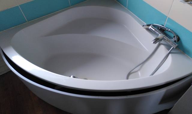 Meubles baignoire d'angle en bon état général avec robinet et tablier